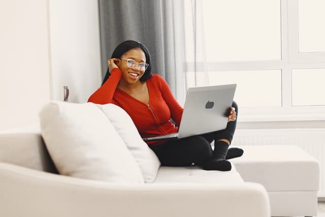 A young woman sitting on a couch with a laptop
